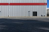 a view of some doors at a building's entrance that is empty outside and has red painted siding