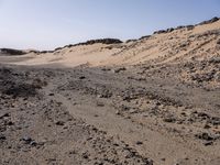 a truck on a dirt road in the desert with rocks and stones on the ground