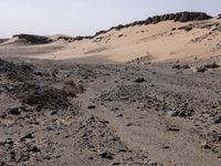 a truck on a dirt road in the desert with rocks and stones on the ground