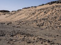 a truck on a dirt road in the desert with rocks and stones on the ground