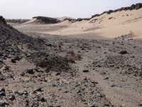 a truck on a dirt road in the desert with rocks and stones on the ground