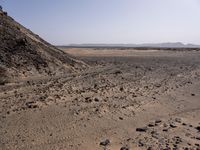 a truck on a dirt road in the desert with rocks and stones on the ground