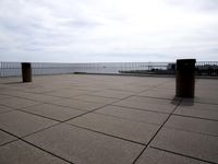 empty floor with a bench, and blue sky over water and beach area, in the background