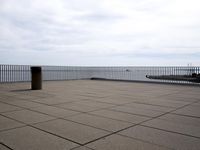 empty floor with a bench, and blue sky over water and beach area, in the background