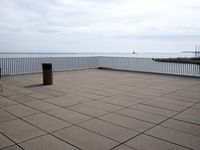 empty floor with a bench, and blue sky over water and beach area, in the background