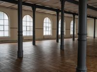 empty floor with multiple large windows in a building, which is surrounded by several brick columns