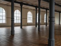 empty floor with multiple large windows in a building, which is surrounded by several brick columns