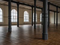 empty floor with multiple large windows in a building, which is surrounded by several brick columns