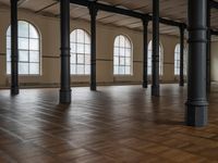 empty floor with multiple large windows in a building, which is surrounded by several brick columns