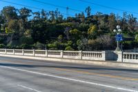 an empty freeway passes by a bridge with lots of trees behind it and two streetlights