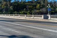 an empty freeway passes by a bridge with lots of trees behind it and two streetlights