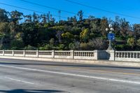 an empty freeway passes by a bridge with lots of trees behind it and two streetlights