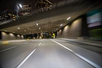 a photo taken of an empty freeway inside the tunnel at night with buildings in the background