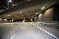 a photo taken of an empty freeway inside the tunnel at night with buildings in the background