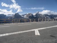 an empty freeway with mountains and mountains in the background, and a sign directing on traffic in front of them