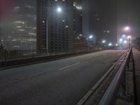 an empty freeway with city lights at night in foggy area with no traffic on the side