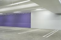 an empty car parking garage with purple wall and white floors with markings on the floor