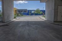 an empty garage with lots of blue walls and trees growing outside of it, and a large blue structure in the background