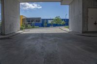 an empty garage with lots of blue walls and trees growing outside of it, and a large blue structure in the background