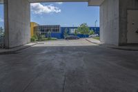 an empty garage with lots of blue walls and trees growing outside of it, and a large blue structure in the background