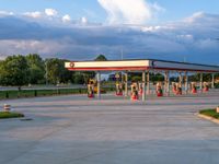 an empty gas station sitting on top of a road next to a lush green hillside