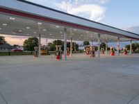 an empty gas station with people standing at the side and looking out to the street