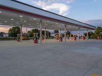 an empty gas station with people standing at the side and looking out to the street