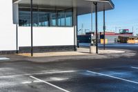 a parking lot next to an empty gas station with some glass walls on the side