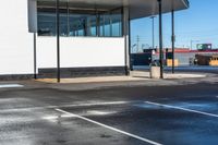 a parking lot next to an empty gas station with some glass walls on the side