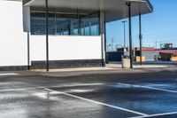 a parking lot next to an empty gas station with some glass walls on the side