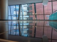 empty glass platform in the middle of an atrium with several buildings outside, reflecting the reflection