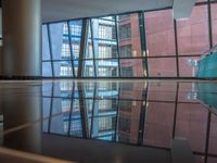 empty glass platform in the middle of an atrium with several buildings outside, reflecting the reflection