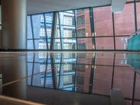 empty glass platform in the middle of an atrium with several buildings outside, reflecting the reflection