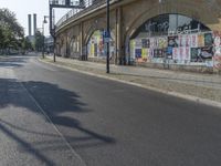 the empty street is full of graffiti as it winds down the road in the sunlight