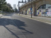 the empty street is full of graffiti as it winds down the road in the sunlight