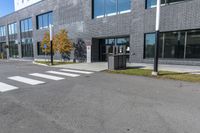 an empty grey parking lot next to a building with a window and metal trash can