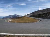 an empty highway goes through mountains in this picture with clear skies above them and grassy hills