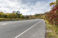 an empty highway with signs on both sides and autumn trees in the background as well