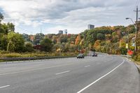 an empty highway with signs on both sides and autumn trees in the background as well