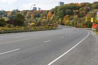 an empty highway with signs on both sides and autumn trees in the background as well