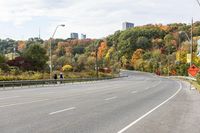 an empty highway with signs on both sides and autumn trees in the background as well