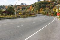 an empty highway with signs on both sides and autumn trees in the background as well