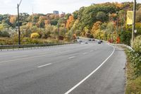 an empty highway with signs on both sides and autumn trees in the background as well