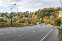 an empty highway with signs on both sides and autumn trees in the background as well