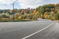 an empty highway with signs on both sides and autumn trees in the background as well