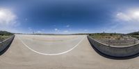 a 360 - angle view of an empty highway with no cars on it under a blue sky