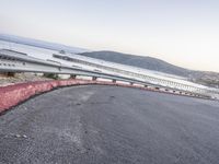 a empty highway near the ocean and a pier near the water's edge with a car on it