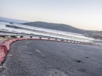 a empty highway near the ocean and a pier near the water's edge with a car on it