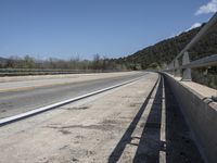 a view from a bridge overlooking trees and a mountain range of hills behind a bridge