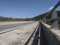 a view from a bridge overlooking trees and a mountain range of hills behind a bridge